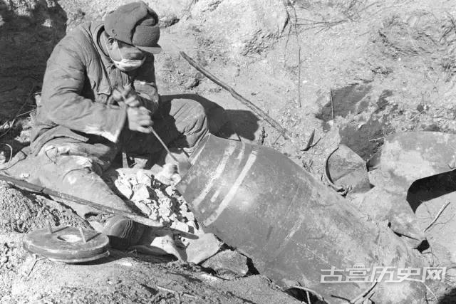 一名中国士兵正在从一枚未爆的美军航空炸弹中挖出炸药。这些炸药将被用于修筑掩体的爆破工程中。