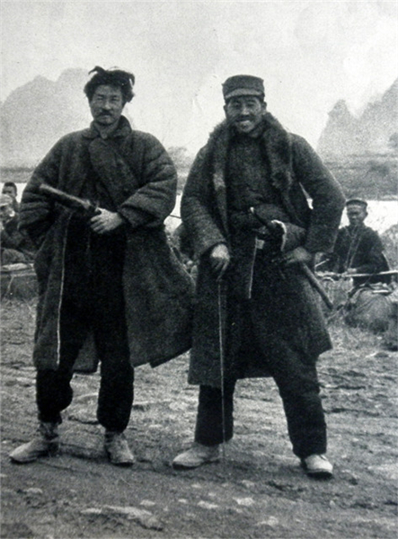 身穿中国军服的日军特工在背对中国难民的时候，悄然亮出身上挂的日本刀拍照留念。